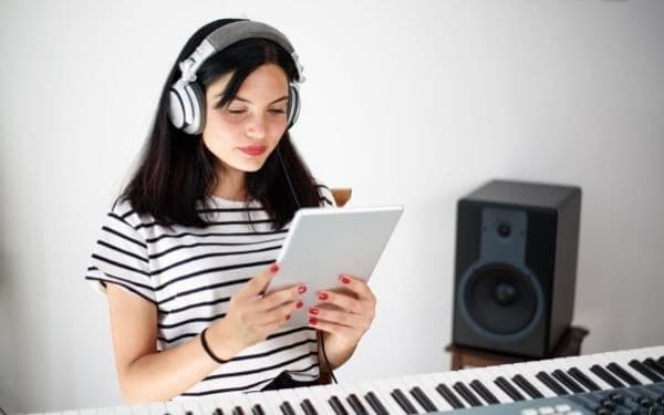 Woman wearing headphones and playing a digital piano