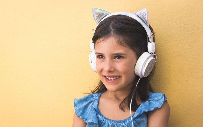 Little girl listening to music with cat ear headphones